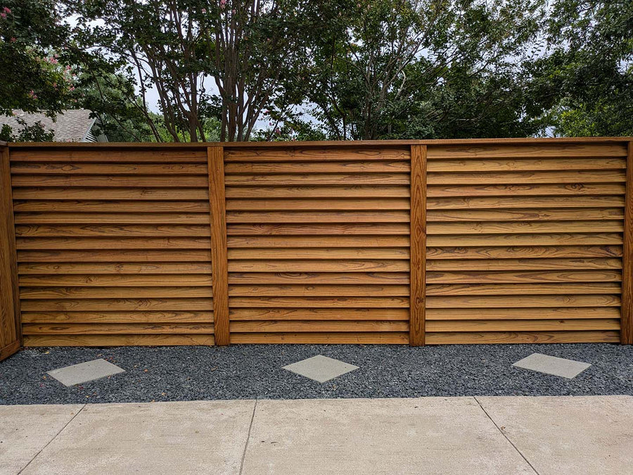 Louvered wood fence providing privacy while maintaining airflow in a backyard.