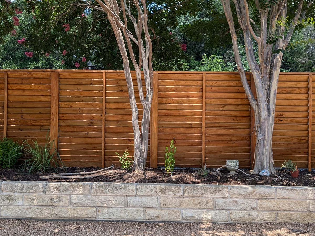 Three sections of six foot tall horizontal louvered fence using 1"x6" wood slats.